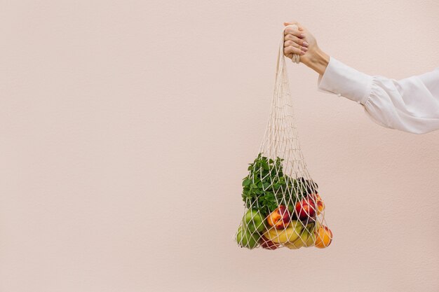 Herbruikbare eco-tas om in te winkelen. String boodschappentas met fruit in de handen van een jonge vrouw