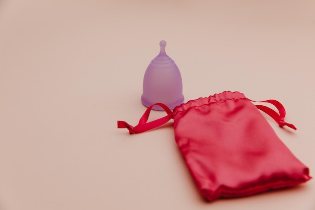 Herbruikbare pastel paarse menstruatiecup en tas op een roze achtergrond alternatieve manier van dameshygiëne...