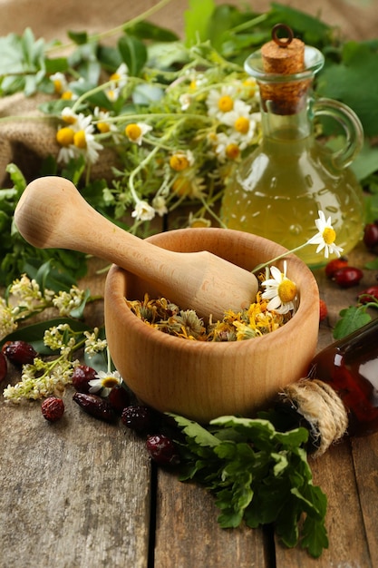 Herbs berries and flowers with mortar on wooden table background