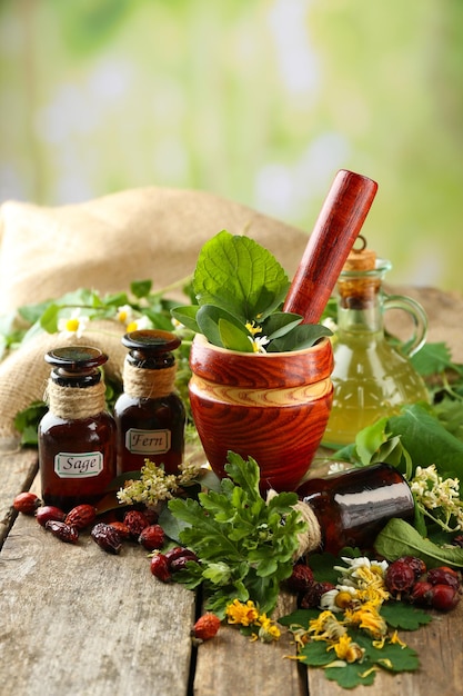 Herbs berries and flowers with mortar on wooden table on bright background