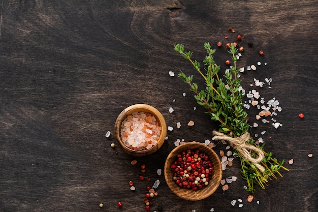 Herbs bunch thyme and condiments on old black wooden table