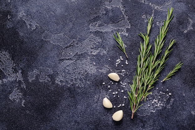 Herbs and condiments on black stone background. Top view with copy space.