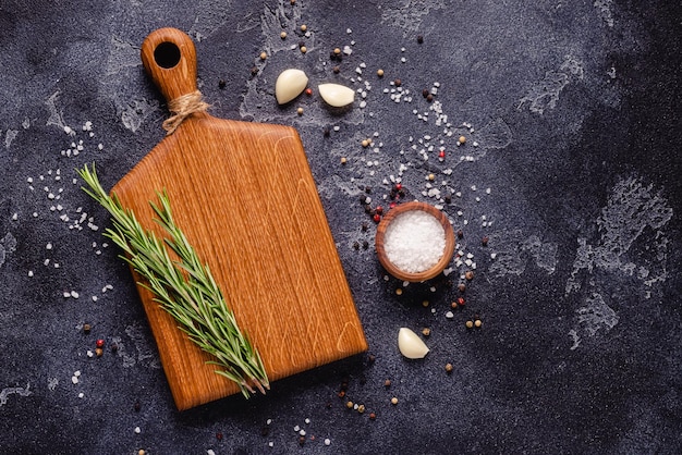 Herbs and condiments on black stone background. Top view with copy space.