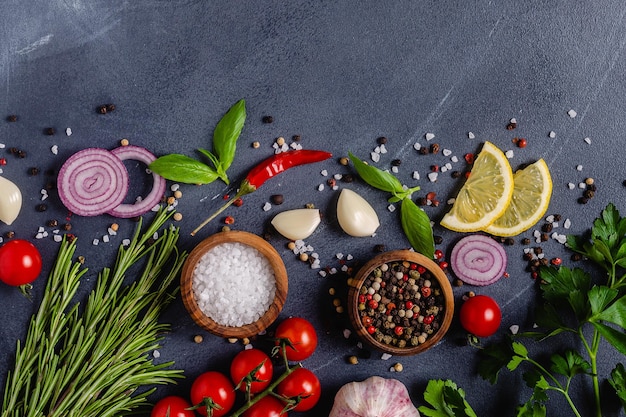 Herbs and condiments on black stone background