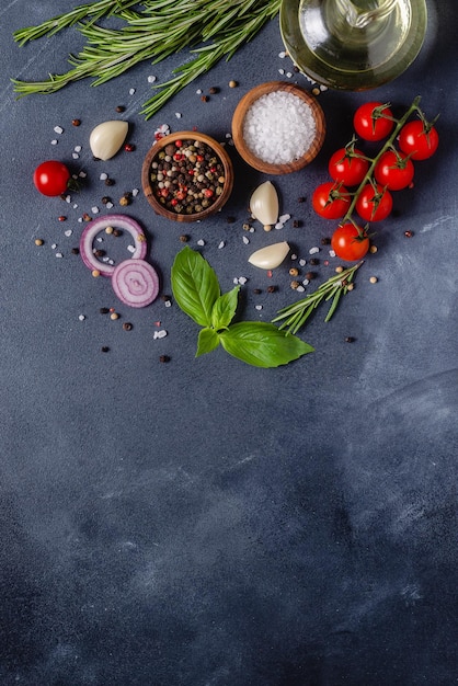 Herbs and condiments on black stone background