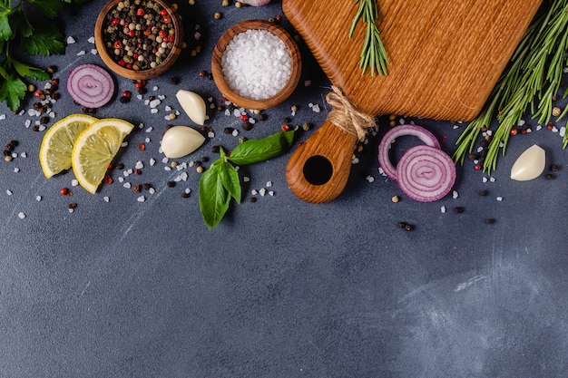 Herbs and condiments on black stone background