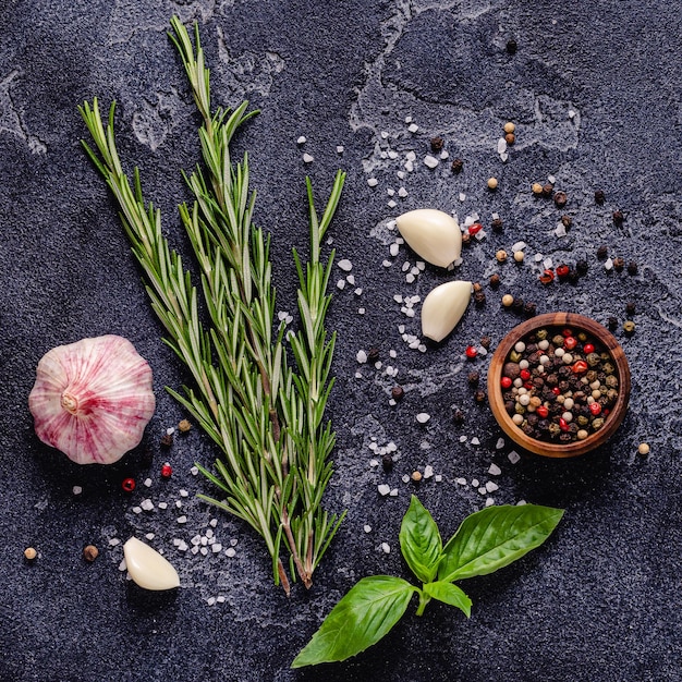 Herbs and condiments on black stone background