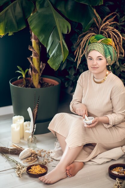 Herbs and oils. Female ayurvedic therapist sitting in a garden and preparing medicine