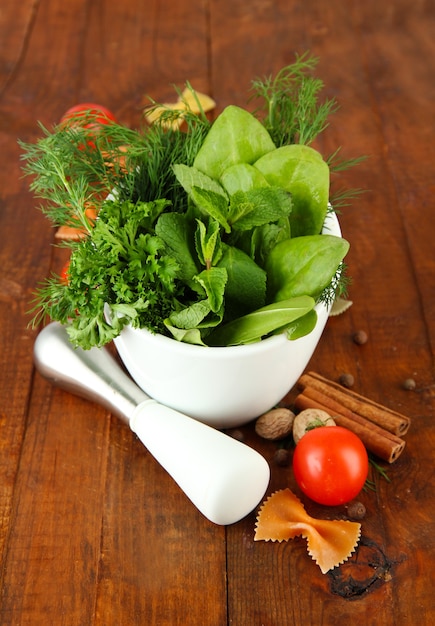 Herbs and spices in ceramic mortar, on wooden wall