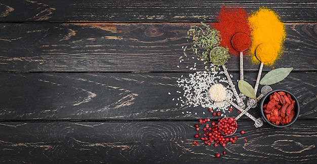 Herbs and spices for cooking in old spoons shot on wooden background.