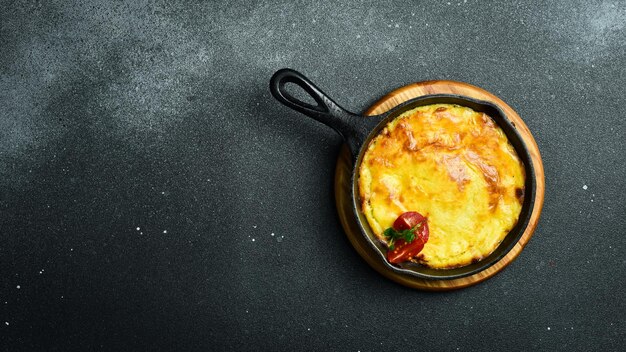 Foto herders pie gehakt puree aardappelen en groenten pan in gietijzeren pan op een zwarte stenen achtergrond