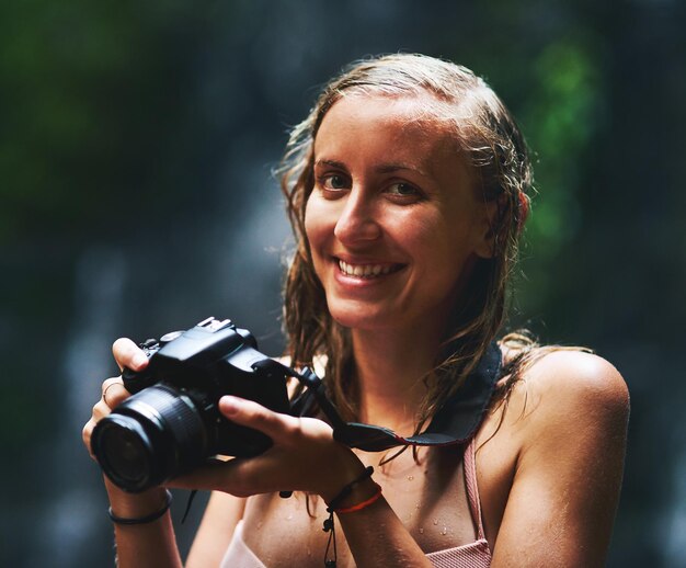 Here to capture every fun filled moment Shot of a smiling young woman holding up a camera and looking happy as can be