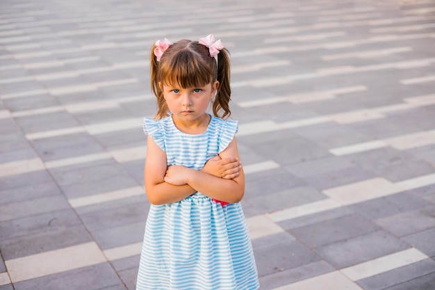 Here is a little girl standing in a public park The child is offended and upset