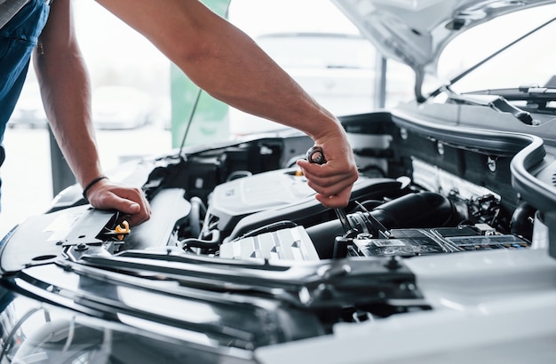 Eccoci qui. processo di riparazione dell'auto dopo l'incidente. uomo che lavora con il motore sotto il cofano.