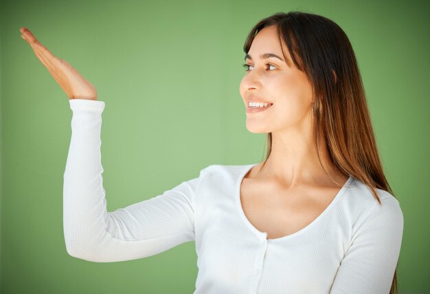 Over here we have the perfect place to chill Studio shot of a young woman holding her hand out against a green background