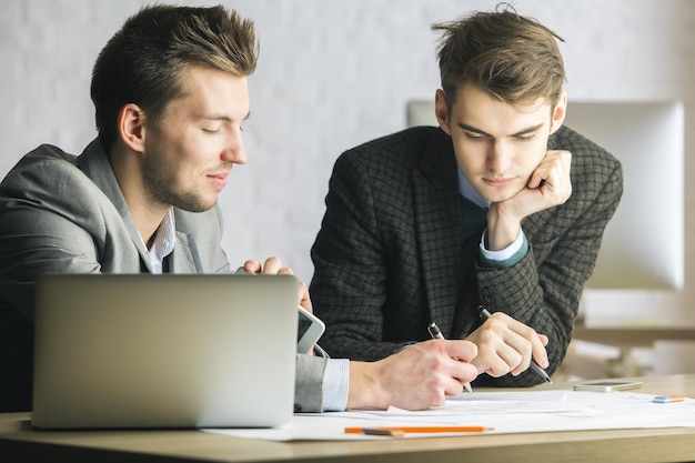 Heren die computer gebruiken en papierwerk doen