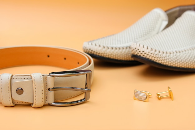 Heren riem, schoenen, manchetknopen op beige achtergrond.