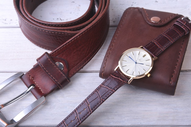 Herenaccessoires met bruine lederen portemonnee, riem en horloge.