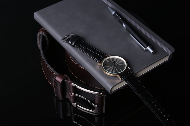 Herenaccessoires met bruine lederen portemonnee, riem en horloge.