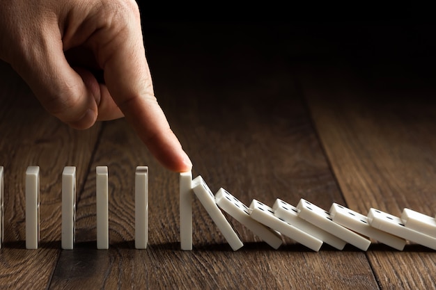 Foto herenhand gestopt domino-effect, op een bruin hout