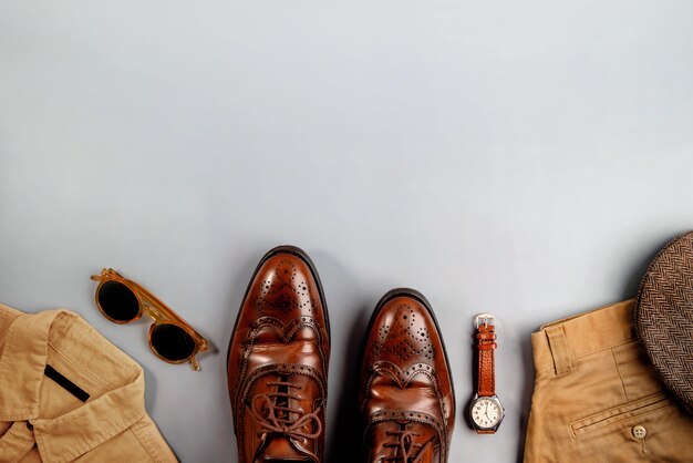 Herenkleding, vaderdagconcept. vintage-stijl. plat lag op lichtgrijze achtergrond. inbegrepen vleugeltips kleding schoenen, hand horloge, platte pet hoed, shirt, broek en zonnebril. stijlvolle mannen. bovenaanzicht