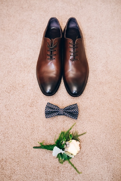 Herenschoenen van bruin leer. bruiloft concept. mannen schoenen, vlinderdas en corsages, bovenaanzicht.