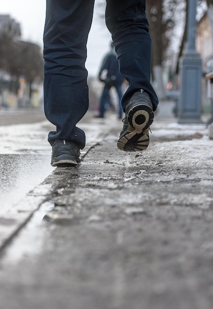 Herenvoeten op de natte asfaltveer