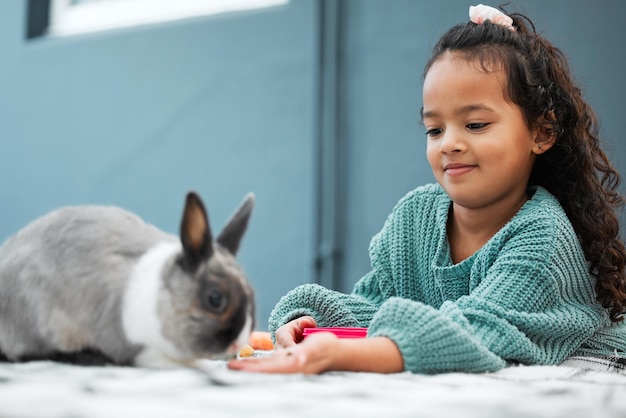 Heres a treat Shot of an adorable little girl feeding her pet rabbit at home