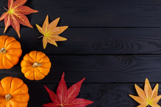 Herfst achtergrond decor van esdoorn bladeren en pompoenen op zwarte houten