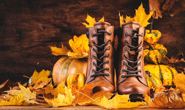 Foto herfst achtergrond met bruine leren laarzen pompoenen esdoorn en eiken bladeren op rustieke houten achtergrond landelijke stijl vrouwelijke stijlvolle schoenen kopieer ruimte banner