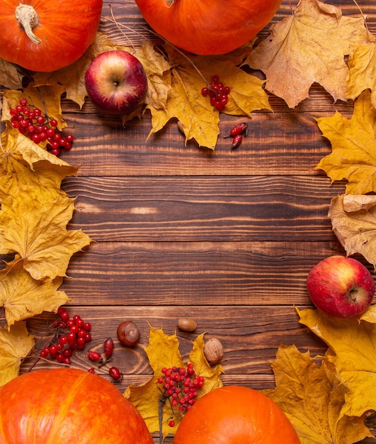 Herfst achtergrond met gele esdoorn bladeren, pompoenen, rode appels en bessen.