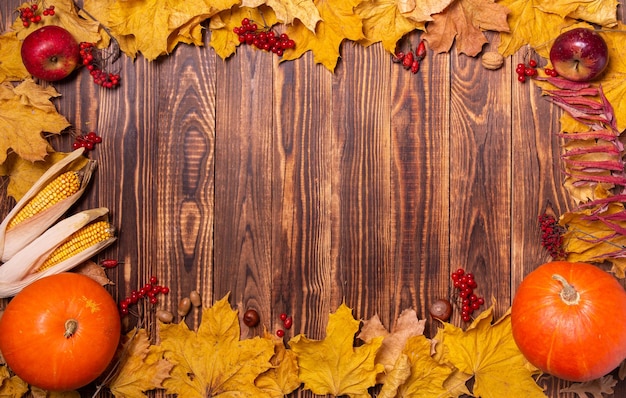 Herfst achtergrond met gele esdoorn bladeren, pompoenen, rode appels en bessen.