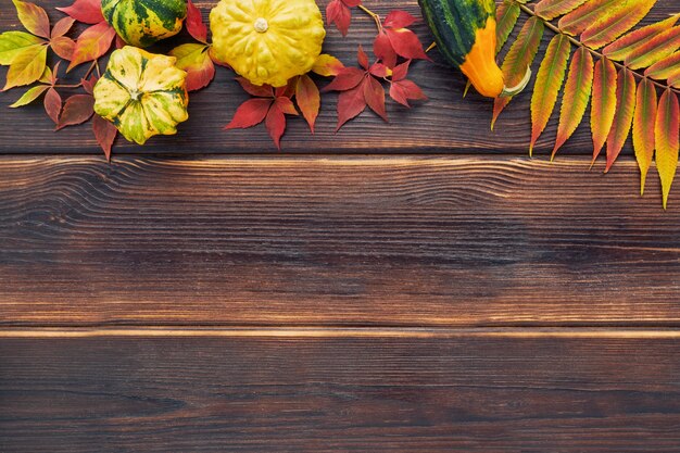 Herfst achtergrond met pompoenen en kleurrijke bladeren op een donkere houten tafel. Gelukkig Thanksgiving-concept. plat leggen