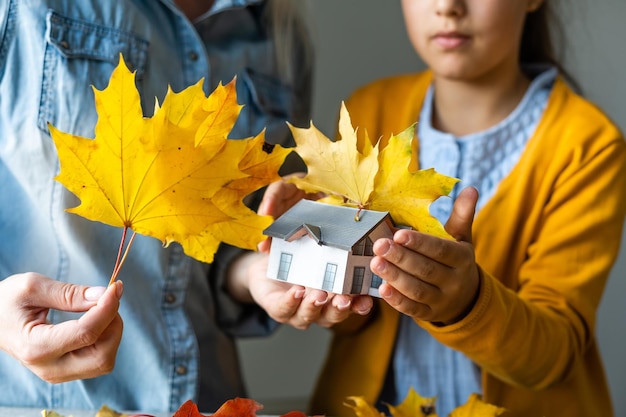 Herfst achtergrond. Speelgoedhuis en gedroogde oranje herfst esdoorn bladeren. Thanksgiving banner kopie ruimte. Hygge stemming koud weer concept. Hallo herfst met familie.