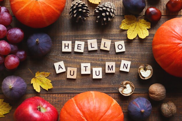 Herfst ansichtkaart met seizoensproducten en opschrift Hello Autumn gemaakt van houten letters