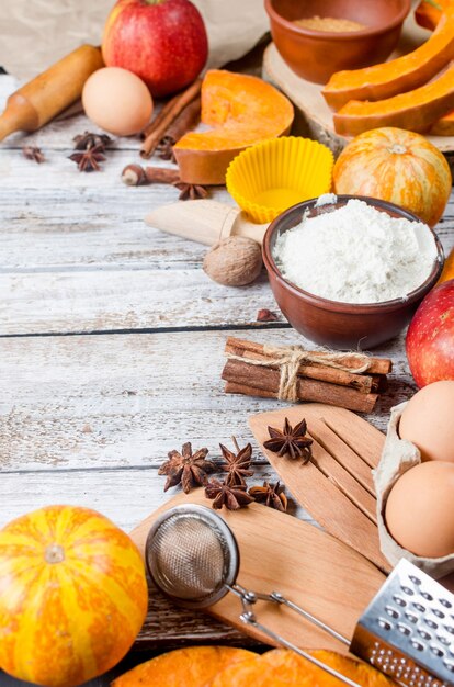 Herfst bakken concept. Frame met pompoen, appel, noten, kaneel, ei en bloem op de houten tafel. Koken bakproces met ingrediënten. bovenaanzicht. kopieer ruimte,