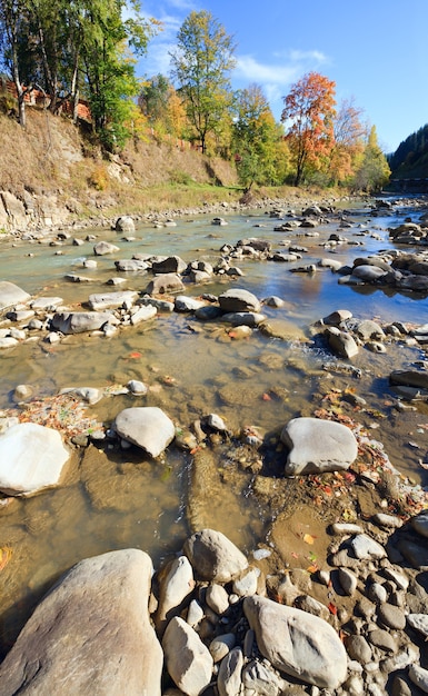 Herfst bergachtig uitzicht op de rivier met enkele stroomversnellingen en steenachtige randen