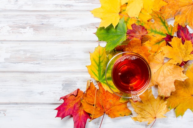 Herfst bladeren en kopje thee op houten tafel