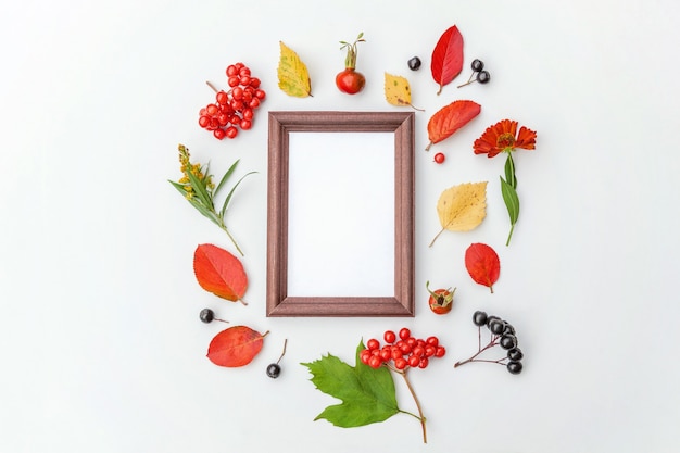 Herfst bloemen compositie. Verticale frame mockup chokeberry rowan bessen kleurrijke bladeren dogrose bloemen op witte achtergrond. Val natuurlijke planten ecologie concept. Platliggend bovenaanzicht, kopieer ruimte