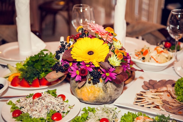 Herfst bruiloft decor in rustieke stijl met bloemen en pompoenen op de tafels van gasten in het restaurant bij een feestelijk banket Tafelbloemstuk op een bruiloft