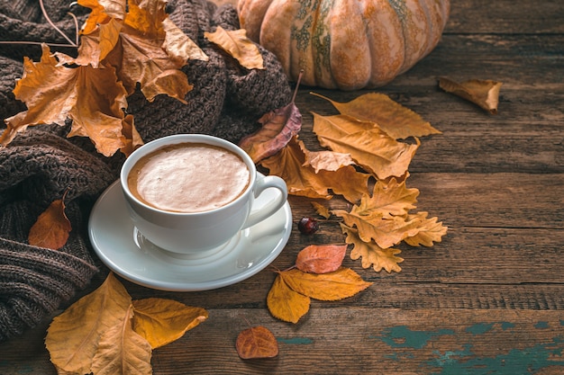 Herfst compositie met koffie gebladerte pompoen en een trui op een houten achtergrond