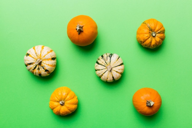 Herfst compositie van kleine oranje pompoenen op gekleurde tafel achtergrond Herfst Halloween en Thanksgiving concept Herfst plat lag fotografie Bovenaanzicht met kopie ruimte