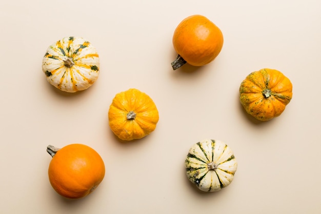 Herfst compositie van kleine oranje pompoenen op gekleurde tafel achtergrond Herfst Halloween en Thanksgiving concept Herfst plat lag fotografie Bovenaanzicht met kopie ruimte