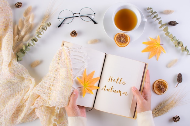 Herfst concept. Vrouw opende boek op tafel met tekst Hallo herfst.