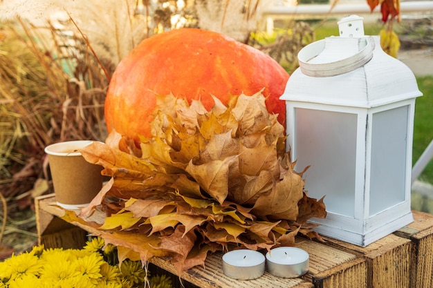 Herfst decor, pompoen, gele bladeren, kopje koffie en kaarsen. Herfst kleuren.