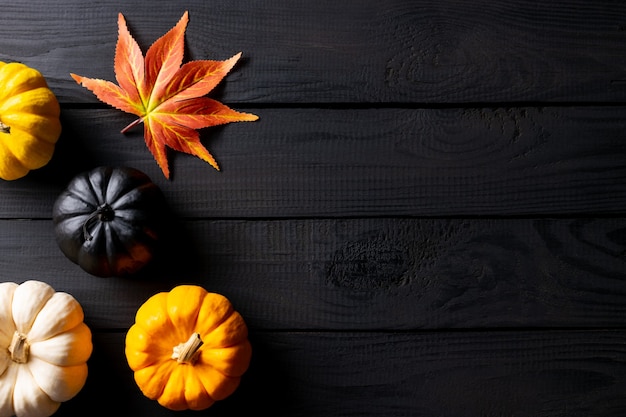 Herfst decor van esdoorn bladeren en pompoenen op zwarte houten tafel. Kopieer ruimte.