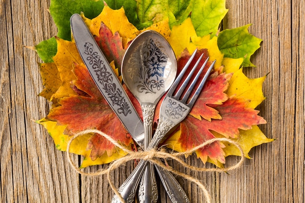 Foto herfst diner plaats instelling voor thanksgiving vakantie met kleurrijke esdoorn bladeren op rustieke houten planken