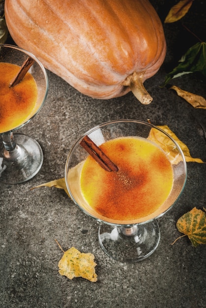 Foto herfst- en winterdranken. thanksgiving en halloween-cocktails. pompoenpastei margarita met kaneelstokje, op zwarte stenen tafel. gezellig huis, met herfstbladeren, plaid, pompoen bovenaanzicht