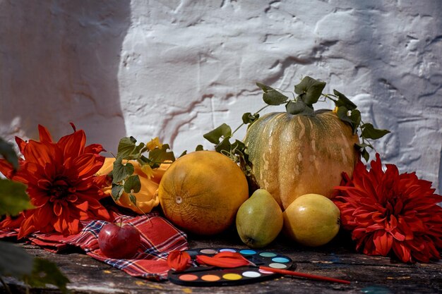 Herfst esthetisch stilleven gele fruit groenten en heldere verven met een borstel pompoen peren appel en meloen Thanksgiving Day concept Herfst stilleven met rode georgine moderne schaduwen