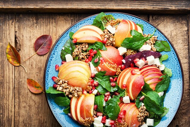 Herfst frisse salade met appel, granaatappel, havermout en fetakaas op rustieke houten tafel